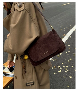 Detailaufnahme der dunkelbraunen Wildleder-Schultertasche mit goldener Aufschrift