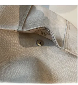Macro shot of silver magnetic buckle and canvas texture on a spacious tote bag