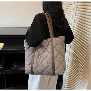 Detail view of quilted tote bag with brown straps in a minimalist lifestyle setting
