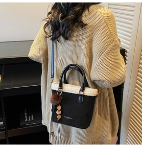 Gros plan du sac seau en daim noir avec bordure en fausse fourrure blanche et broderie