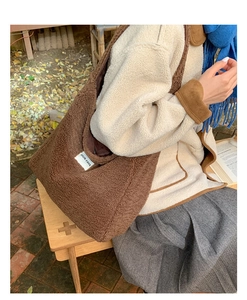Detail of a large brown faux shearling tote bag with OUR FAVE label in an autumn setting