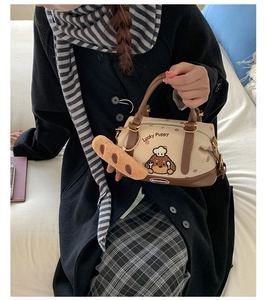 Détail du sac Boston en toile avec imprimé chien et breloque baguette en peluche