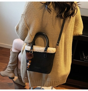 Détail du sac seau en daim noir avec bordure en fausse fourrure blanche et pompon bohème