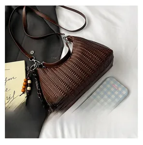 Close-up of brown woven hobo bag texture with slim leather strap and silver hardware