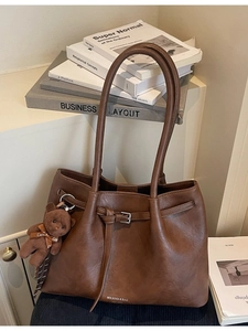 Vintage brown leather tote bag with a plush bear charm and minimalist branding
