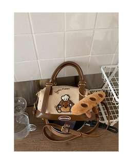 Détail de la broderie chiot et breloque baguette en peluche sur un sac Boston beige