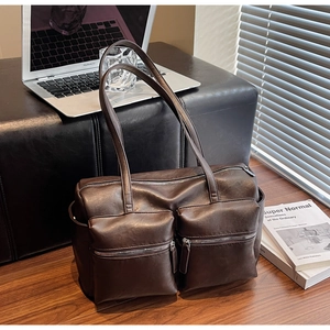 Detail of dark brown faux leather shoulder bag with two front zipper pockets