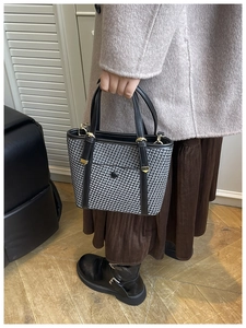 Dettaglio della borsa tote intrecciata con manici in pelle nera ed eleganti dettagli oro