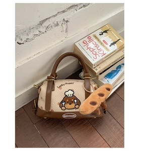 Détail du sac Boston avec broderie Lucky Puppy et charm baguette en peluche sur parquet
