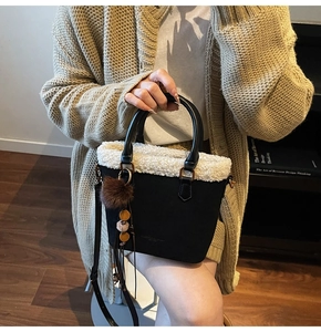 Détail du sac seau en daim noir avec bordure en fausse fourrure blanche et pompon