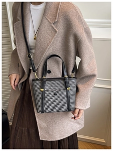 Dettaglio di una borsa tote intrecciata con manici in pelle nera e finiture dorate