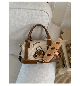 Détail du sac Boston avec broderie Lucky Puppy et breloque baguette sur tissu crème