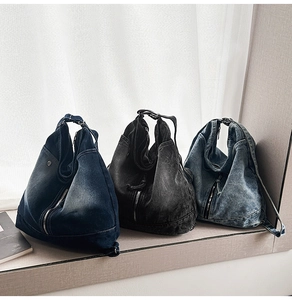 Detailed macro view of three washed denim sling bags with metal zippers and buckles