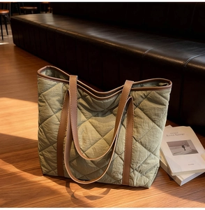 Detail of army green quilted tote bag with brown leather handles on leather sofa