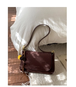 Nahaufnahme der dunkelbraunen Wildleder-Schultertasche mit goldener Schnalle und Anhänger