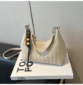 Detailed view of cream pleated hobo bag with unique wooden bead charm and metallic zipper