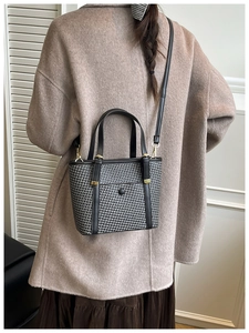 Dettaglio della borsa tote intrecciata con manici in pelle e finiture in metallo dorato