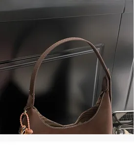 Detail view of smooth handle and fine white contrast stitching on dark brown bucket bag