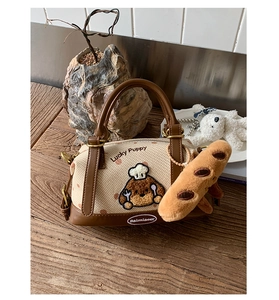 Détail du sac Boston avec broderie Lucky Puppy et petit pendentif baguette en peluche