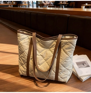 Detailed close-up of quilted tote bag featuring large diamond stitching and brown straps