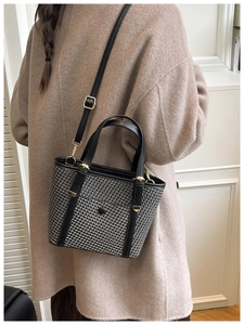Dettaglio borsa in tweed con finiture in pelle nera e fibbia dorata su cappotto cammello