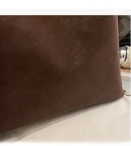 Close-up of brown litchi texture leather handbag with gold fashion lettering