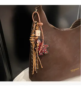 Detailed macro view of dark brown pebbled leather texture with charms and gold lettering