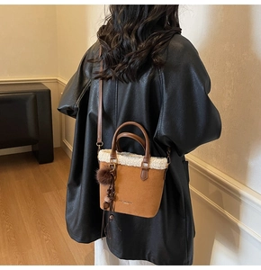 Détail du sac en daim marron avec bordure en peau lainée et breloque peluche décorative