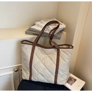 Close-up of cream quilted tote bag with diamond stitching and dark brown leather handles