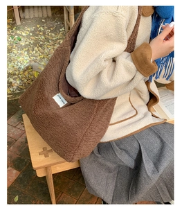 Detail of dark brown faux shearling tote bag with a minimalist white fabric label