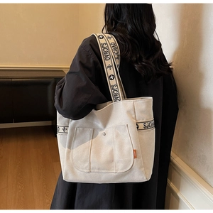 Detail of wide woven shoulder strap with letter patterns on a canvas tote bag