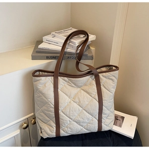 Detail of quilted tote bag with cream rhombus pattern and brown leather straps