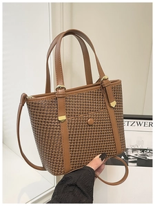 Dettaglio della trama intrecciata e del manico in pelle di una borsa vintage marrone con fibbia
