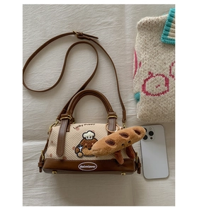 Détail du sac Boston en tissu beige avec broderie de chien et breloque peluche