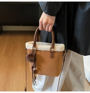 Détail du sac seau en daim marron avec bordure en fourrure blanche et pompon