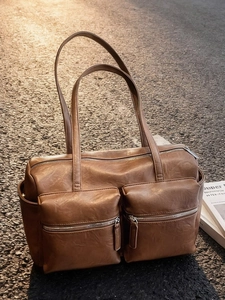 Chic brown faux leather shoulder bag with front zipper pockets on an outdoor road