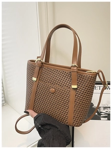 Dettaglio della borsa tote intrecciata marrone con manici in pelle e finiture dorate