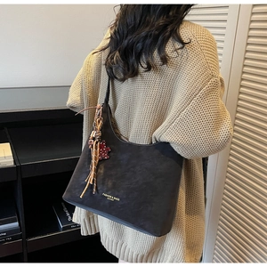 Detail of dark brown matte leather shoulder bag with red leopard heart tassel charm