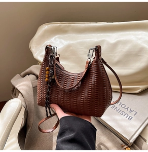 Close-up of dark brown woven texture shoulder bag with decorative wooden bead charm
