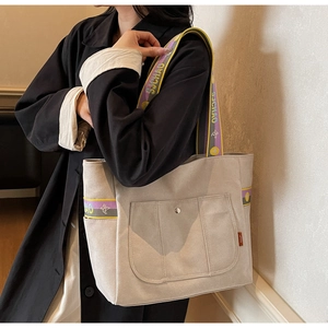 Detail view of beige canvas tote bag with jacquard strap and functional pockets