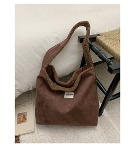 Detail of plush brown suede tote bag with faux shearling lining and embroidered logo