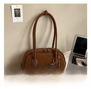 Detail of vintage brown suede Boston bag with donut charm in a minimal desk setting