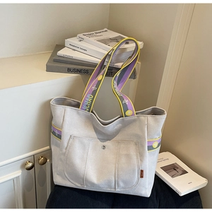 Detail view of a large canvas tote bag with contrast shoulder strap and front pocket