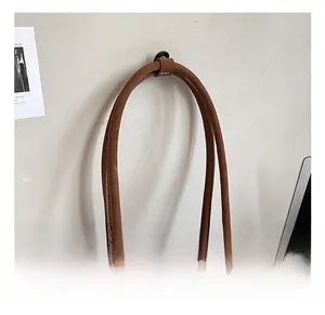 Detail of a brown matte shoulder bag with white contrast stitching and double zippers