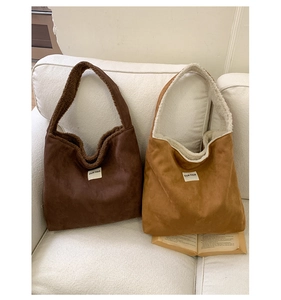 Close-up of suede tote bags with fleece lining and white brand label on a white sofa