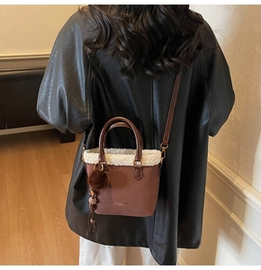 Détail du sac seau en daim avec bordure en peau lainée et glands en cuir marron