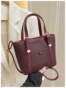 Dettaglio della borsa tote bordeaux intrecciata con finiture dorate e manici chic