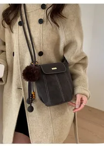 Detail of dark brown bucket bag with white contrast stitching and tassel charm