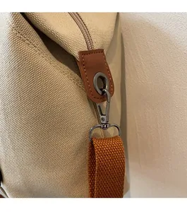 Detail of metal swivel hook with orange woven strap and leather trim on canvas bag