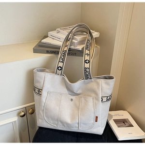 Close-up of minimalist canvas tote bag with floral strap detail and front pocket